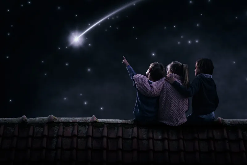 3 kinderen op een dak, kijkend naar de sterren